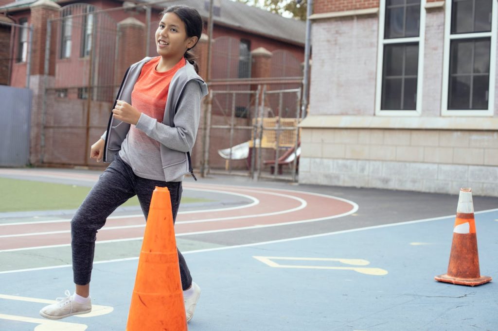 Full body of active Hispanic schoolgirl in sportswear running while having physical education class